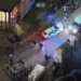 Avon and Somerset Police A drone shot of a city street at night time. A police car and a police van are visible and a number of people are milling about. Two white vans are also visible, and light is spilling from the windows of one building.