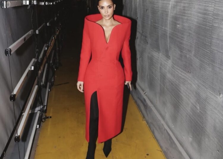 Kim Kardashian in a bold red Balenciaga tailored coat styled with black boots, a striking take on modern celebrity new year outfits.