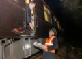 Jack Boskett A picture of a person wearing an orange jacket delivering newspapers to the side of the Royal train.