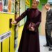 Duchess Sophie wearing a maroon coat and bag pressing a button on a colorful wall