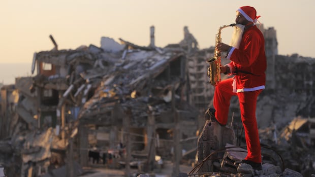 Father and son dress as Santa, visit Gaza tent city with gifts, music to celebrate New Year