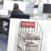 Newspapers stacked in a display stand with a "California Post" sign, in an office setting.