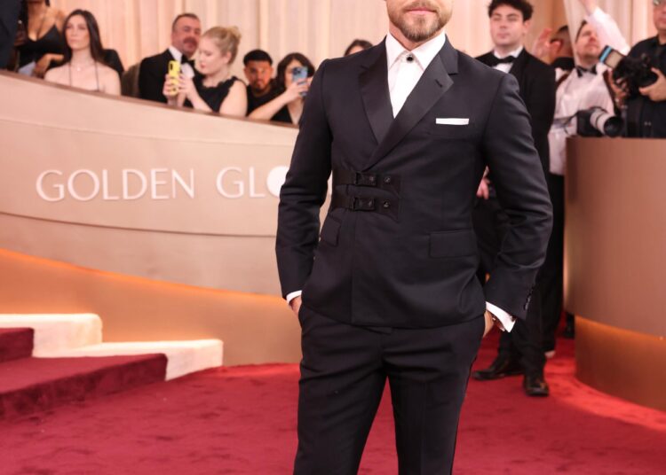 Derek Hough, in a black tux, walks the red carpet.