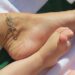 a closeup view of a foot and an infants foot next to each other with an anklet visible