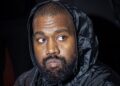Kanye West wearing a black hooded jacket.