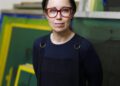 A woman standing in front of green canvases