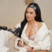 Kim Kardashian speaking into a microphone on a podcast.