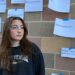 A teenager gazes into the distance, disregarding the tragic headlines posted behind her. Social media has exponentially increased our exposure to news, causing many people to become desensitized to displays of tragedy.