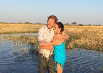 Couple standing in water in a grassy landscape