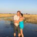 Couple standing in water in a grassy landscape