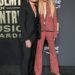 Keith Urban in a black suit and Nicole Kidman in a red sparkly pantsuit at the 58th Academy of Country Music Awards.