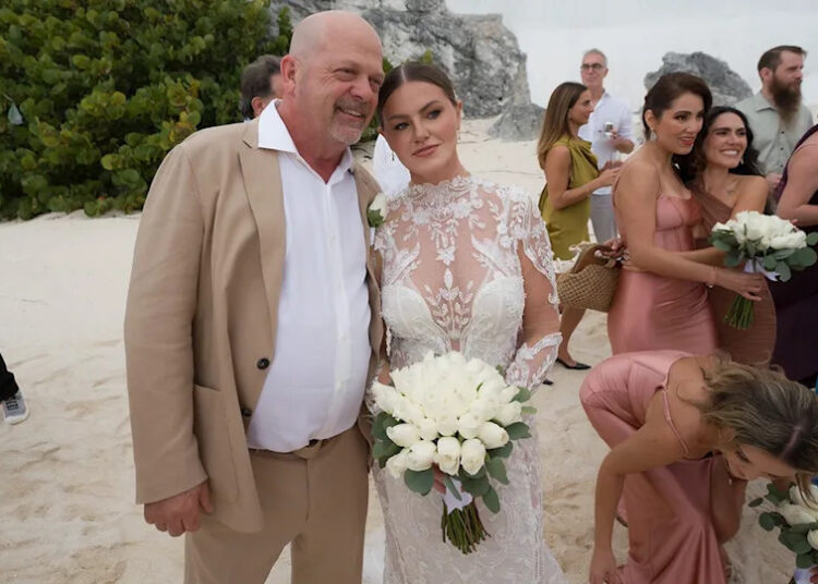Rick Harrison wears tan suit with wife Angie in white bridal gown.