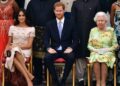 Meghan, Duchess of Sussex, Prince Harry and Queen Elizabeth sit on chairs in front of other people