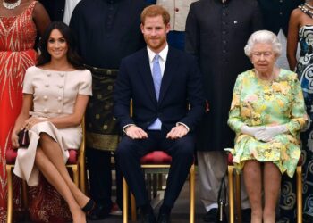 Meghan, Duchess of Sussex, Prince Harry and Queen Elizabeth sit on chairs in front of other people