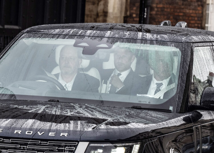 Prince Harry in a black car with two other men, leaving Clarence House.