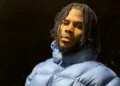 XL Recordings Jim Legxacy pictured outdoors at night in a light blue puffa jacket