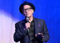 Rob Schneider holding a microphone on stage