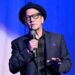 Rob Schneider holding a microphone on stage