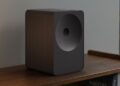 A black Samsung Music Studio 7 wireless speaker on a wooden shelf at a 3/4 angle.