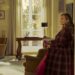 Sarah Jessica Parker, as Carrie Bradshaw, stands against a wall in her living room in "And Just Like That."