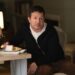 A man sits at a table eating cake.