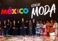 Politicians in black suits and Indigenous Mexicans in colorful tradition clothing stand on a stage under the words "México está de moda"