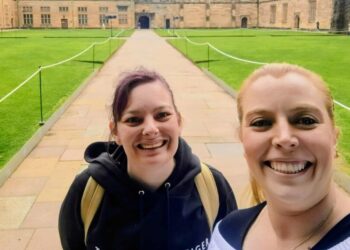 Lauren and Brianna take a smiling selfie in the middle of a university grounds.