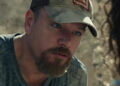 Matt Damon as Bill Baker wearing a hat and speaking to someone in Stillwater