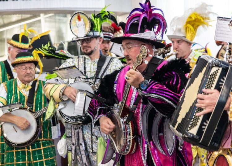 Members of various Mummers clubs’ string bands play their instruments in colorful outfits