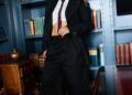 a person in a formal outfit with a modern twist stands in a library