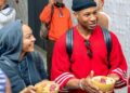 Mohamed Finando / Oxygen Africa US actors Meagan Good and Jonathan Majors being welcomed at Conakry Gbessia International Airport.  They were presented with kola nuts. Kola nuts hold deep cultural significance in West Africa, symbolising hospitality, peace, friendship, and life.  They are used in crucial social rituals like weddings, funerals, and negotiations.   The couple are smiling, chatting and wearing relaxed clothing.