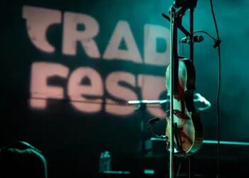 A fiddle is placed on a stand on a stage in low lighting.