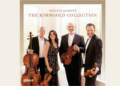 Four musicians from the Pacifica Quartet stand indoors holding string instruments in front of a window; the album is titled The Korngold Collection.