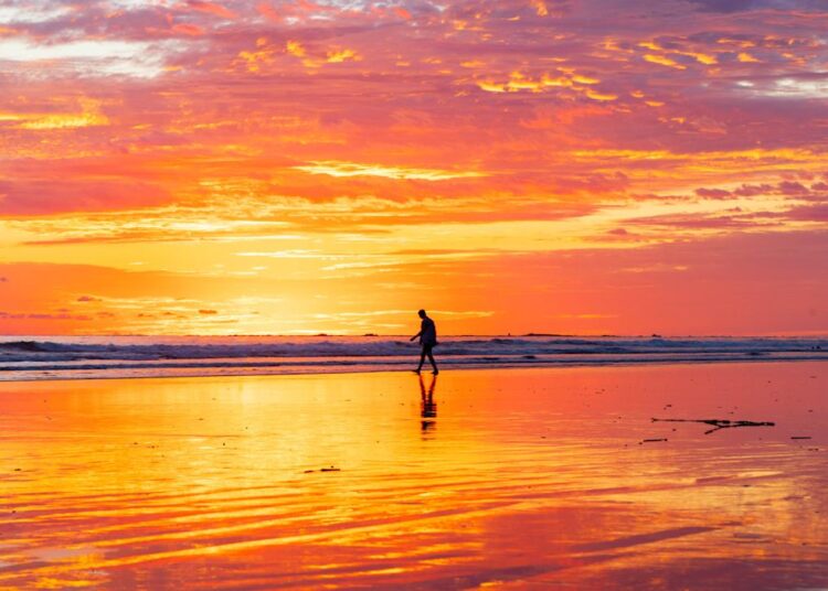 A man walks on the beach at sunset in Uvita.