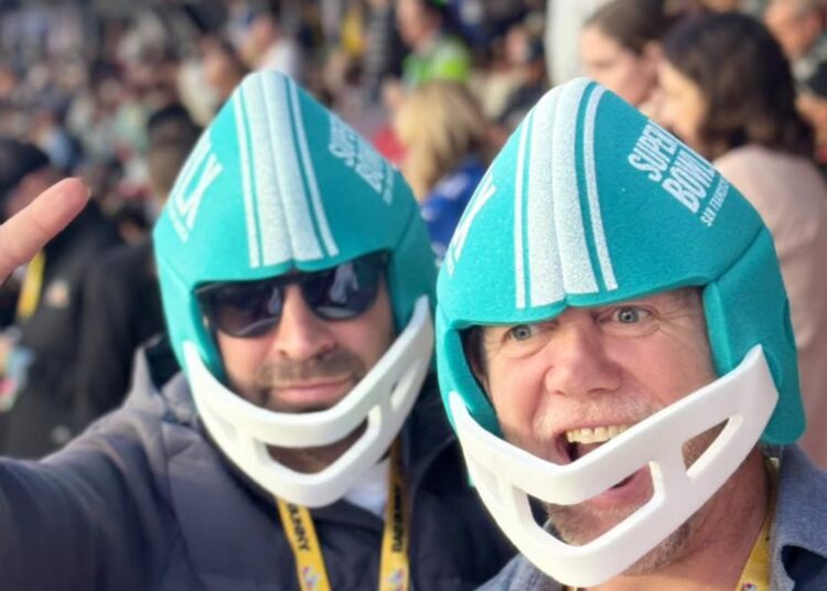 Mike Tindall wearing a blue helmet and cheering with a friend at the Super Bowl