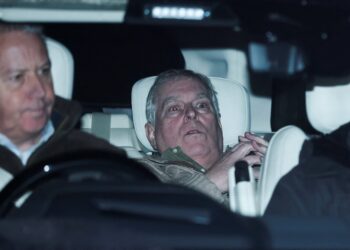 Andrew Mountbatten-Windsor lies down with wide eyes in a car, a man in front of him.