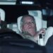 Andrew Mountbatten-Windsor lies down with wide eyes in a car, a man in front of him.