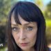 Juliette Bryant, now aged 43, has long brown hair with a fringe and stands outside with a serious expression