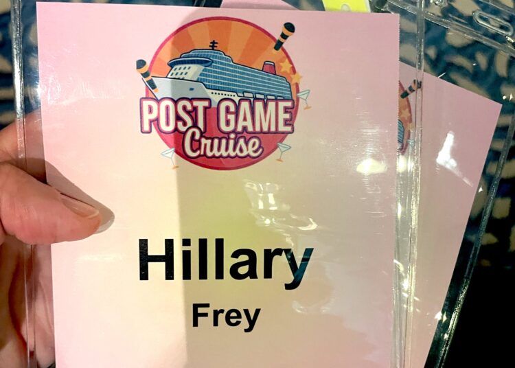 The author holding a pink cruise lanyard, which has her name and the words "Postgame Access Pass."
