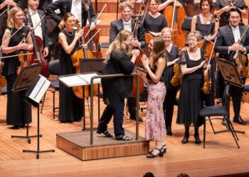Ella Macens approaches the conductors podium on the stage of the opera house. She is greeted by conductor Simone Young.