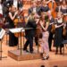 Ella Macens approaches the conductors podium on the stage of the opera house. She is greeted by conductor Simone Young.