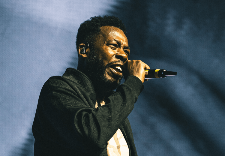 GZA of Wu-Tang Clan performing live on stage at Amalie Arena in Tampa during a June 2025 concert.