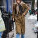 person walking on a city sidewalk dressed in a long coat and scarf