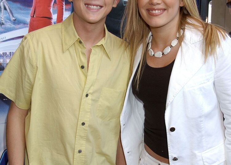 Image may contain Frankie Muniz Hilary Duff Angie Harmon Clothing Shirt Pants Adult Person Blouse Blonde and Hair