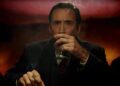 a man sitting at a table with a drink and a cigarette