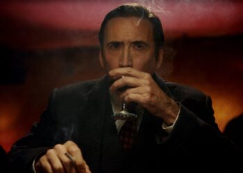 a man sitting at a table with a drink and a cigarette