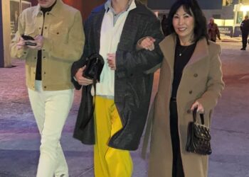 group of three people walking in a city setting at night