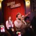 John Legend performing in front of a crowd of people with Kelly Clarkson and Druski.