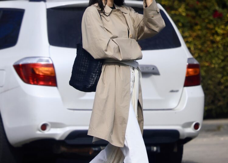Kendall Jenner embraces high vamp ballet flats, white pants, and a woven bag