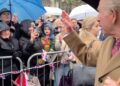 A heckler in a grey hat and holding a blue umbrella asked King Charles about Andrew's connection to Epstein